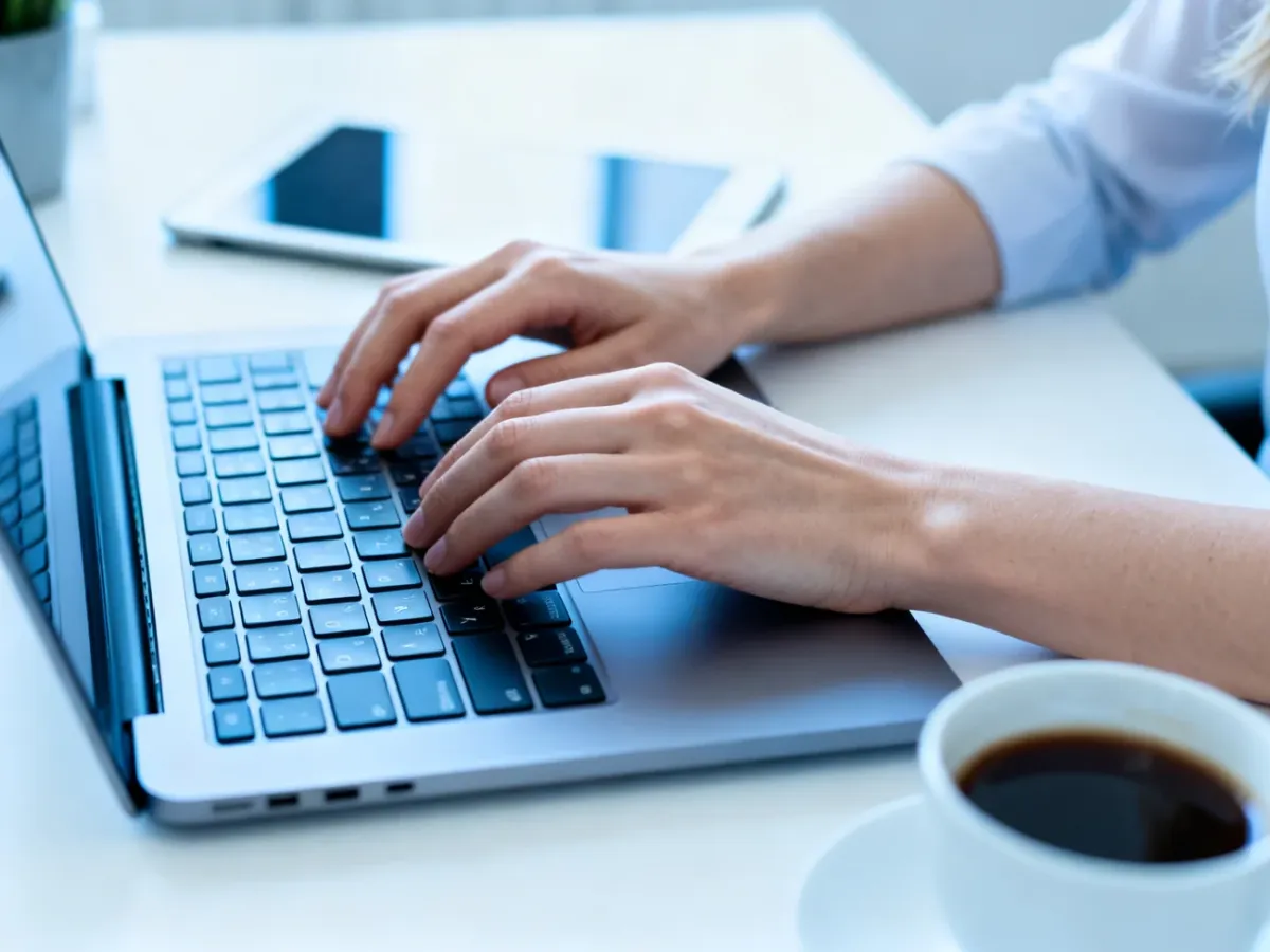 Dłonie kobiety pracującej na laptopie w nowoczesnym biurze, przygotowującej przelew w systemie podzielonej płatności.